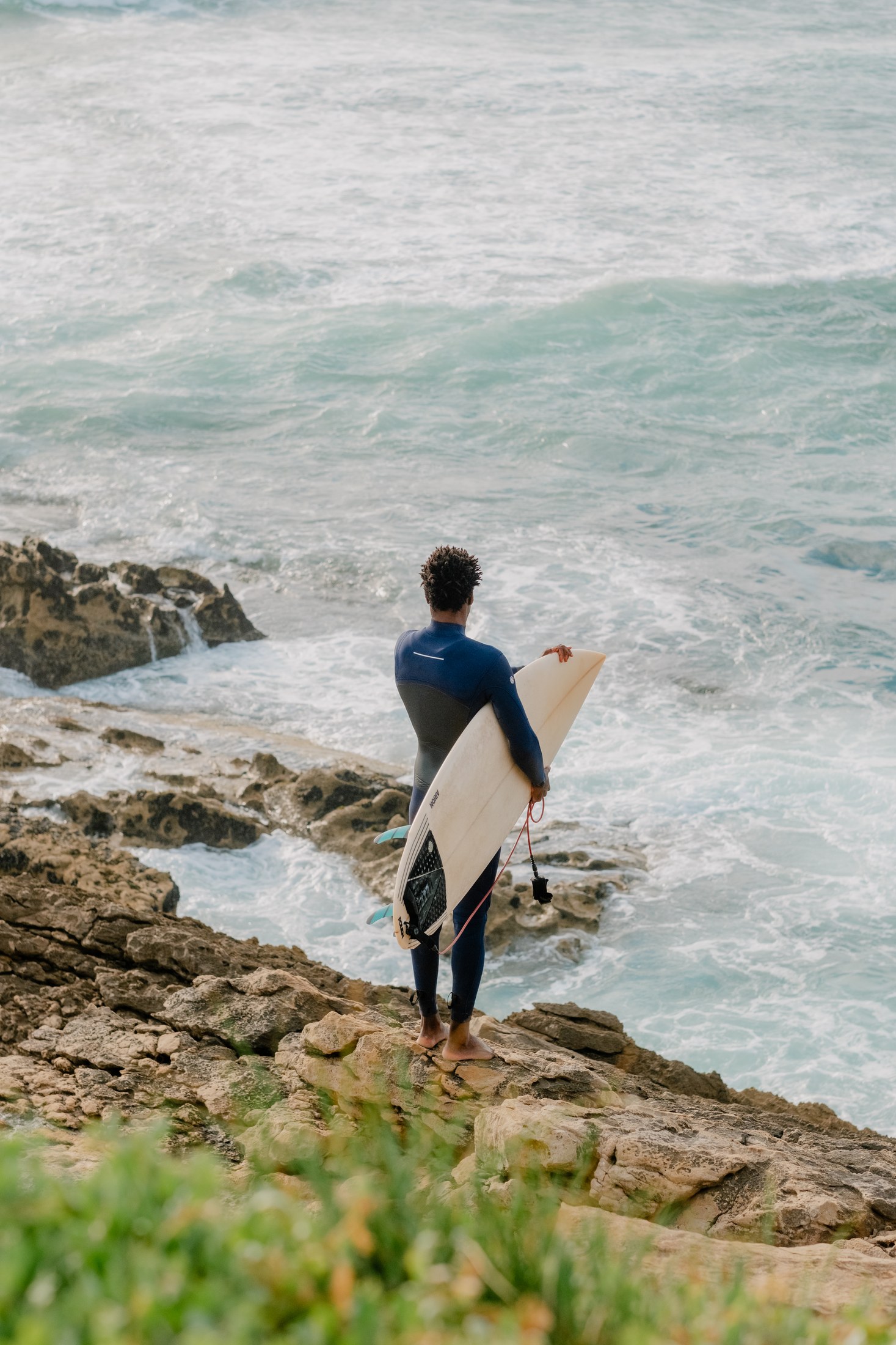 Surfer descending across the rocks