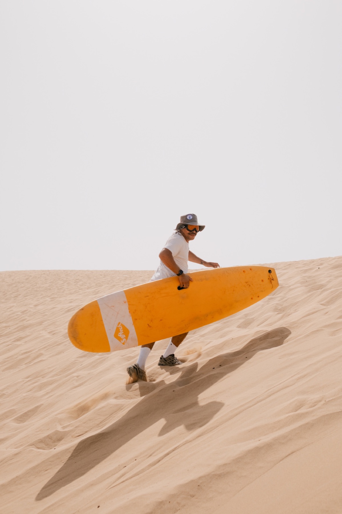 Surfer running across the dunes