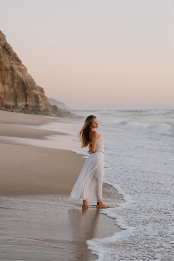 Woman in white walking at the shoreline
